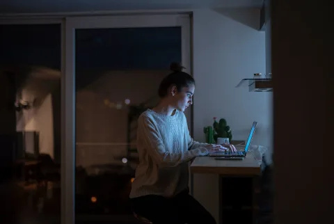   Kvinde, der arbejder på en bærbar computer i sit hjem