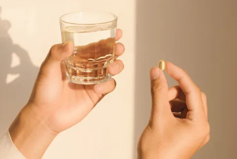   Nogen der holder et glas vand og et kosttilskud