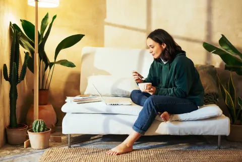   Kvinde, der sidder på sofaen og spiser