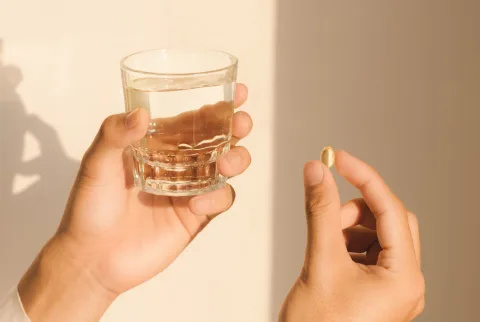   Nogen der holder et glas vand og et kosttilskud