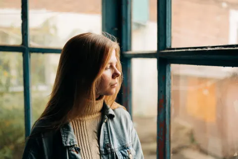   kvinde kigger trist ud af vinduet