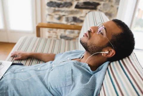   Mand slapper af på en sofa og lytter til musik