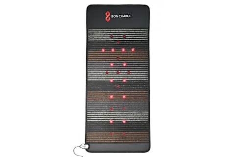 Инфракрасный коврик Bon Charge PEMF Max лежит на земле, горят красные огни.
