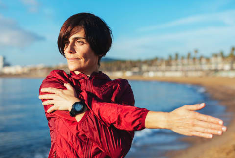  40's woman exercising and stretching outside on the beach