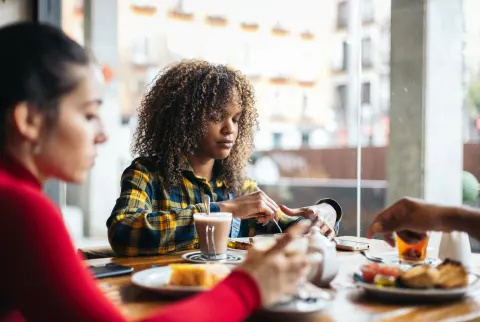 Kvinna som äter frukost med vänner tittar på tallriken