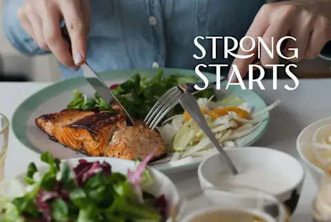   Kvinde spiser en laksefilet med blandet salat