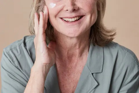 Unerkennbare Frau in den Fünfzigern trägt Feuchtigkeitscreme auf ihr Gesicht auf