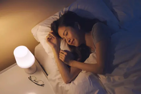 Kvinner som sover i sengen med et nattlys