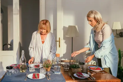   Mor og voksen datter dækker middagsbordet
