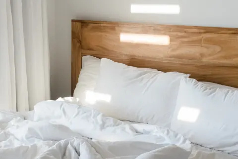 cama desfeita com lençóis brancos