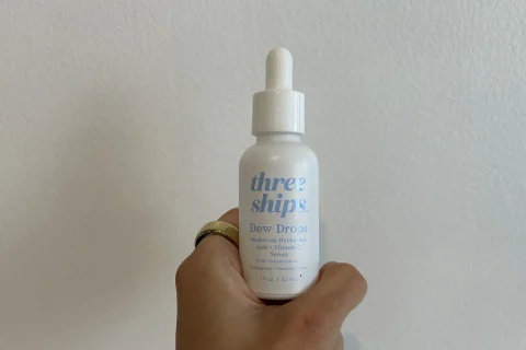   الكاتب's hand holding three ships dew drops bottle