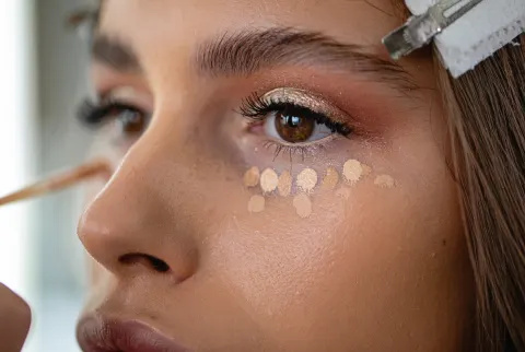Kvinde med prikker af concealer klar til at blande sig under øjnene