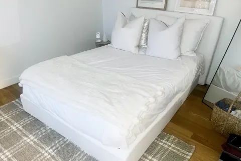   Probador de revisión de colchones de látex orgánico de Plushbeds, cama completamente hecha con cuatro almohadas y cabecera
