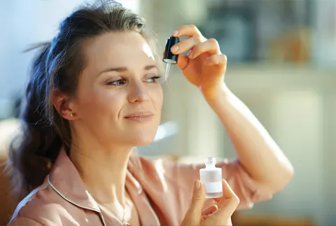   ældre kvinde påfører serum i ansigtet