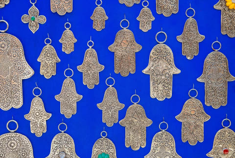   sininen seinä, joka on peitetty hopeisella hamsa-koristeella