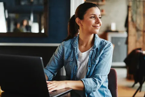   Smilende kvinde arbejder på sin bærbare computer.