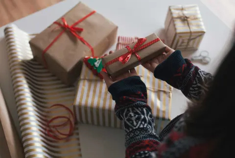   Nő, aki egy kis becsomagolt ünnepi ajándékot tart