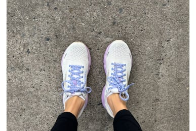 Обзор беговых кроссовок Brooks Ghost 15 с белым и фиолетовым цветом на ногах бегунов на тротуаре рядом