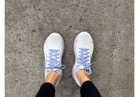 Обзор беговых кроссовок Brooks Ghost 15 с белым и фиолетовым цветом на ногах бегунов на тротуаре рядом